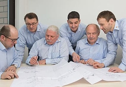 Image of a group of people sitting around a table working on papers