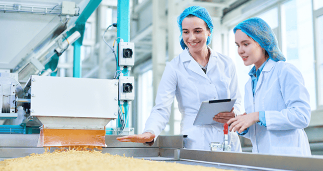 Image of Two Women with hairnets on looking at food on conveyor