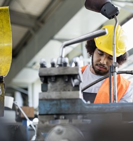 Young manual worker working on machinery